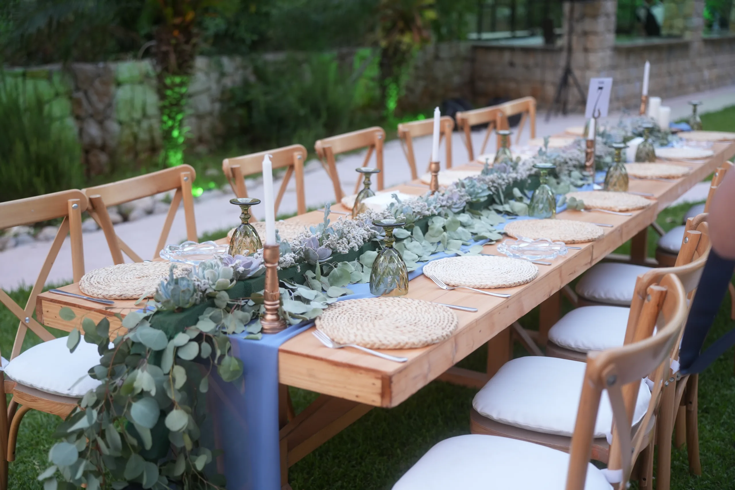 Rustic wedding setup with table runner made out of an arrangement of succulents, flowers and eucalyptus, coupled with candles.