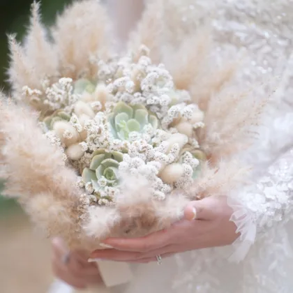 picture of a bride holding a succulent bouquet. fully airy, white and pastel colors