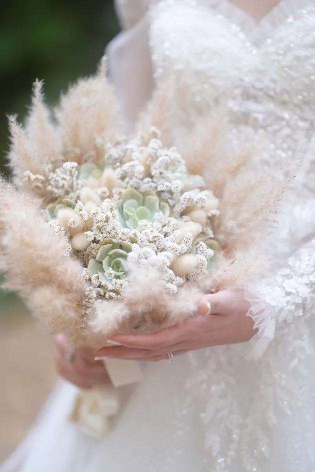 picture of a bride holding a succulent bouquet. fully airy, white and pastel colors